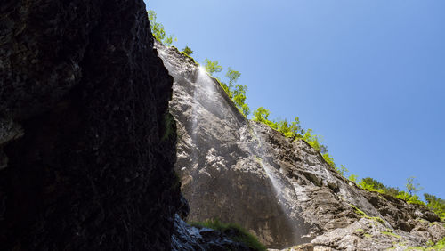 Low angle view of waterfall against clear sky