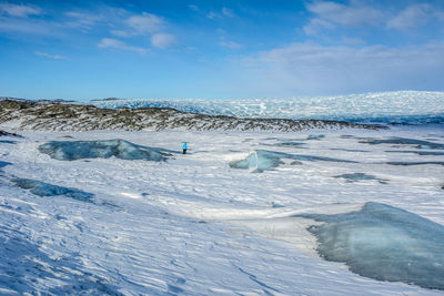 Scenic view of snow covered shore against blue sky