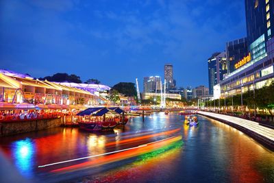 Illuminated bridge over river amidst buildings in city at night