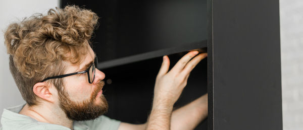 Side view of young man looking through window