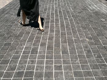 Low section of woman walking on cobblestone