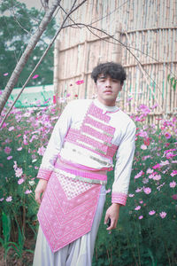 Full length of young man standing against pink flowering plants