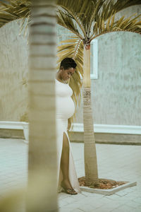 Low section of pregnant woman standing by tree