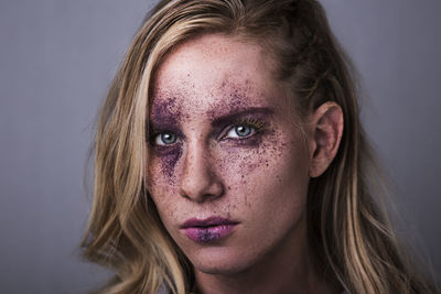 Close-up portrait of beautiful woman against gray background