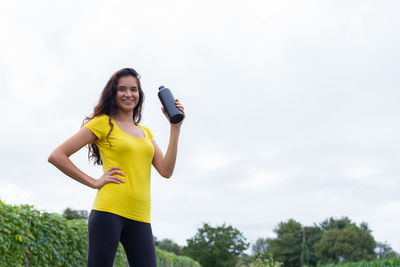 Young woman exercising against sky