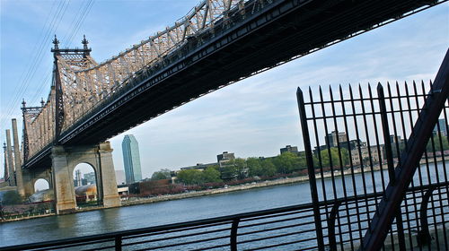 Bridge over river by buildings against sky
