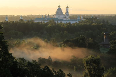 View of trees and buildings against sky during sunset