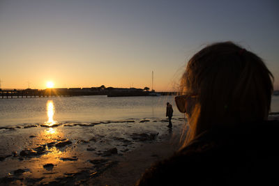 Rear view of woman on beach at sunset