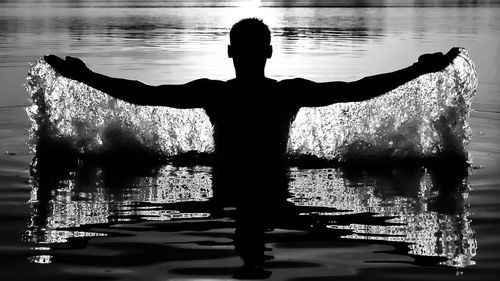 Rear view of silhouette man standing in swimming pool