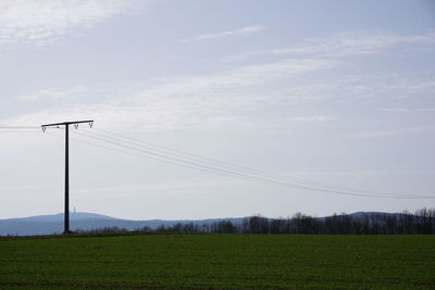 Low angle view of electricity pylon on field against sky