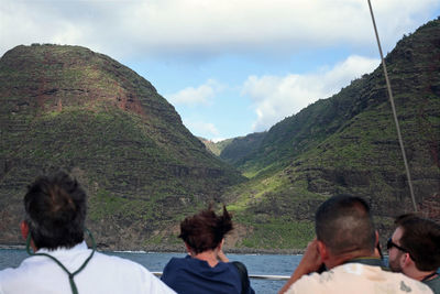 Rear view of people looking at mountains against sky