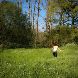 Rear view of woman running on field