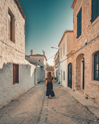 Rear view of woman walking on street amidst buildings