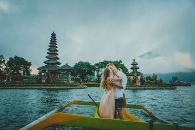 Couple in outrigger boat on lake against temple