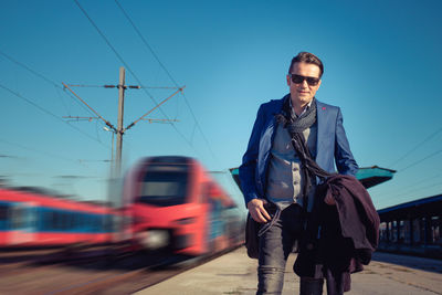 Portrait of smiling handsome man standing at railroad station platform