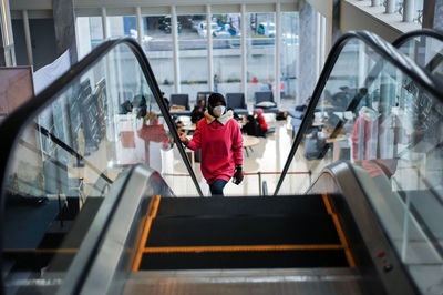Low angle view of young woman sitting on escalator