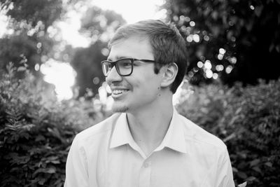 Portrait of smiling young man standing against trees