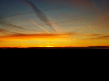 Silhouette landscape against orange sky