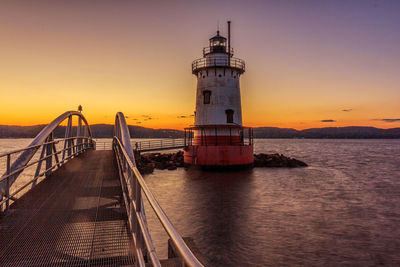 Lighthouse in front of calm sea at sunset