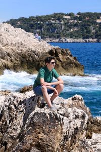 Man sitting on rock by sea