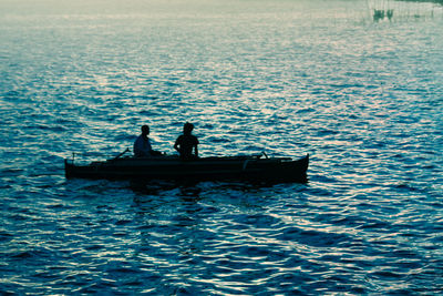 Silhouette men on boat in sea