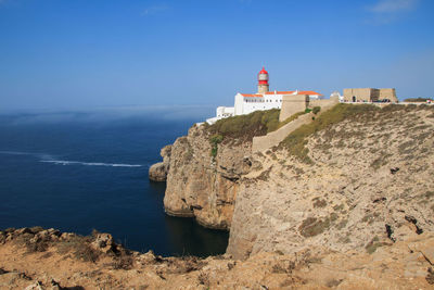 Lighthouse by sea against clear sky