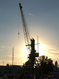 Low angle view of silhouette cranes against sky at sunset