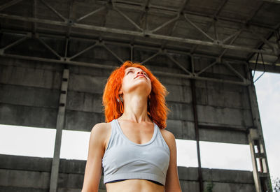 Redhead woman looking up while wearing sports bra