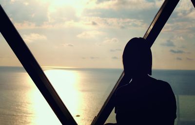 Silhouette man standing by sea against sky during sunset