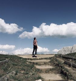 Rear view of young woman looking away while standing against sky