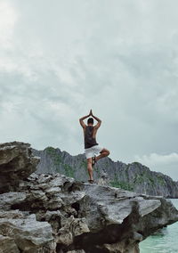 Rear view of man standing on rock against sky