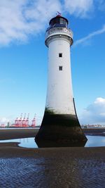 Lighthouse by sea against sky