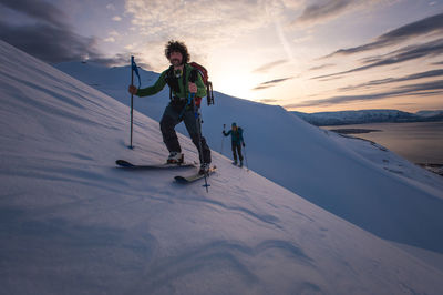 Man and woman backcountry skiing in iceland with water behind