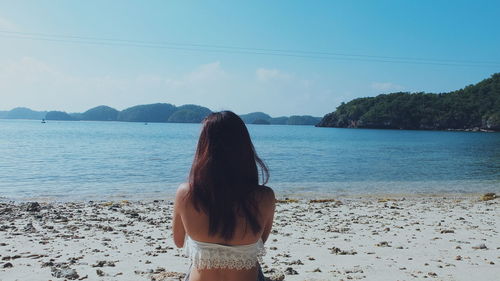 Rear view of woman at beach against sky