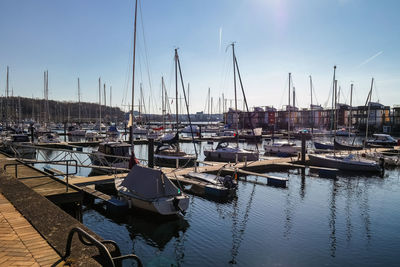 Boats moored at harbor in sea against sky