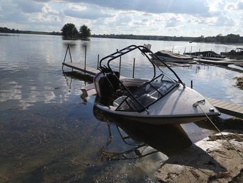 Boat moored on lake against sky