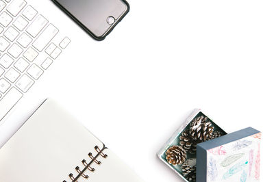 High angle view of computer keyboard with mobile phone and book over white background