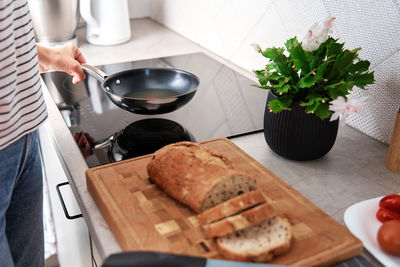 Woman cutting loaf of bread with large knife