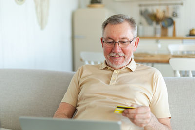 Young man using mobile phone while sitting on sofa at home