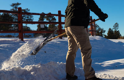 Close up of man taking snow off the road in the middle of winter with blue sky