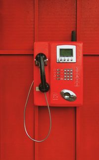 Close-up of telephone booth against red wall
