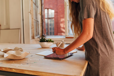 Midsection of woman standing by table at home