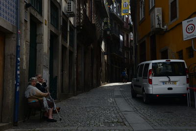 Man sitting on street amidst buildings in city