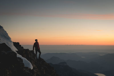 Man looking at view while standing on mountain against sky during sunset