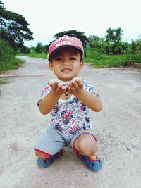 Portrait of innocent boy crouching on road