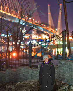 Portrait of woman standing against illuminated lights at night