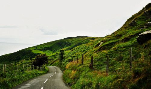 Road leading towards mountain against sky