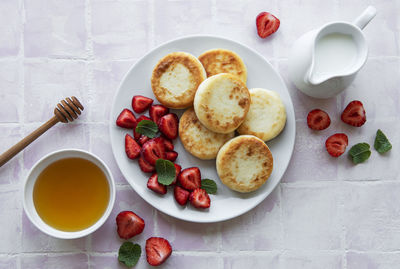 Cottage cheese pancakes, ricotta fritters on ceramic plate with fresh strawberry. 