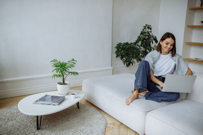 Young woman sitting on sofa at home