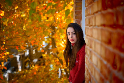 Portrait of young woman standing against tree